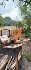 Strawberry kettle heating over a fire on a sandy shore