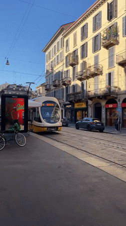 Paper boats float in Milan street puddles amid tram activity