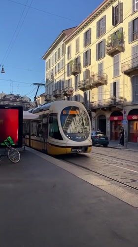Paper boats float in Milan street puddles amid tram activity
