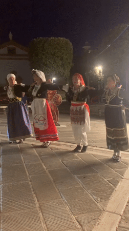 Folk dancers in traditional costume perform under a Tuscan dusk sky