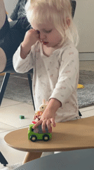 Child plays with toy truck while rubbing eye