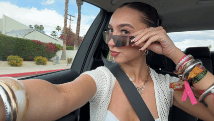Woman removes sunglasses while sitting in car in Palm Springs