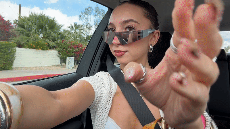 Woman removes sunglasses while sitting in car in Palm Springs