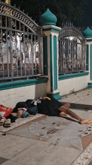Person observed resting on sidewalk in Lhokseumawe, Indonesia