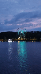 Ferris wheel, bridges, and barges on a waterway at dusk