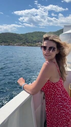 Woman in red dress enjoys boat ride near Lepetane, Montenegro