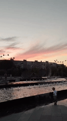 Waterfront park at golden hour, fountains and skyline.