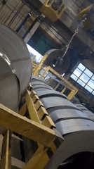 Factory interior with stacked metal rolls documented by witness