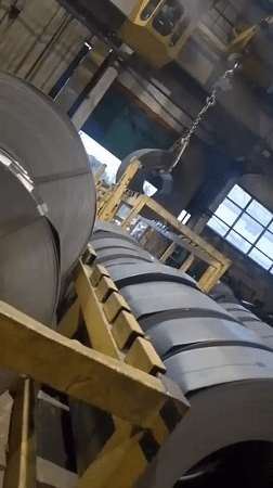 Factory interior with stacked metal rolls documented by witness