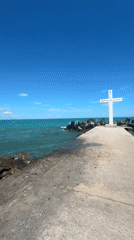 White cross and stone monument at a coastal memorial site
