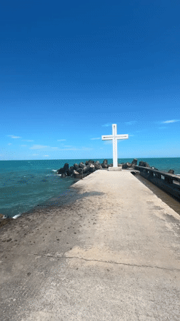 White cross and stone monument at a coastal memorial site