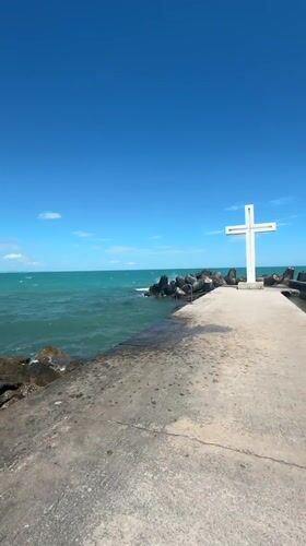 White cross and stone monument at a coastal memorial site