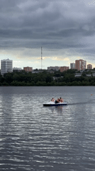 Stormy skies over Izhevsk pond on a busy waterfront afternoon