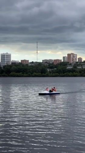 Stormy skies over Izhevsk pond on a busy waterfront afternoon