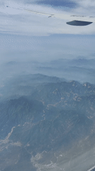 Passenger captures aerial view of mountains, river, town from airplane