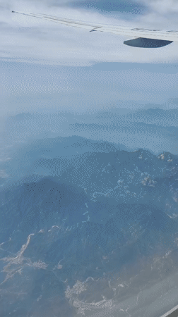 Passenger captures aerial view of mountains, river, town from airplane