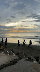 Soccer, fishing boats, and beachgoers at Bateetimoh under stormy skies