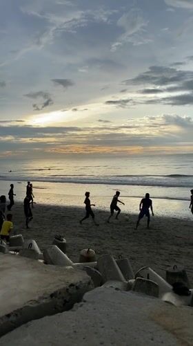 Soccer, fishing boats, and beachgoers at Bateetimoh under stormy skies