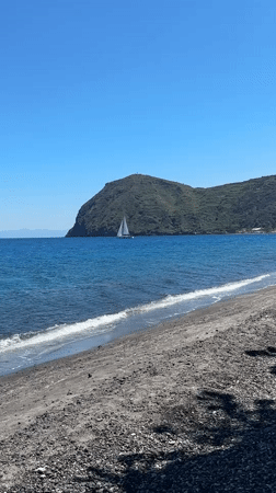 Sailboat glides across turquoise waters near Lipari, Italy