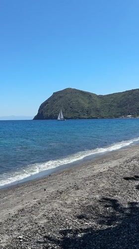 Sailboat glides across turquoise waters near Lipari, Italy