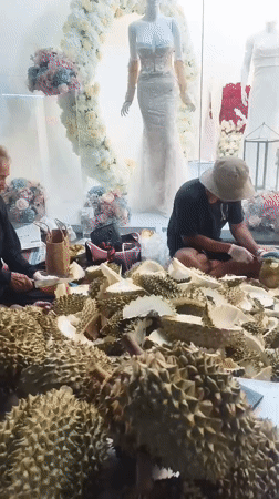 Durian vendors process fruit on Thailand street at night