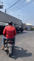 Motorcycle riders pass through an Indonesian flag-lined neighborhood street