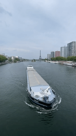 Cargo barge cruises the Seine with the Eiffel Tower behind
