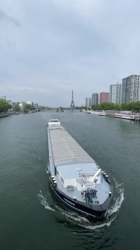Cargo barge cruises the Seine with the Eiffel Tower behind