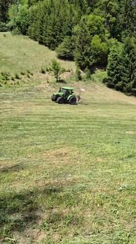 Woman documents tractor mowing field in Austrian countryside