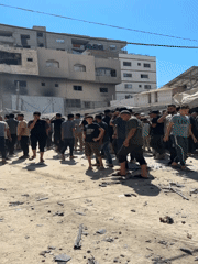 Crowd gathers around destroyed vehicle in Gaza City street