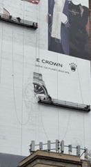 Workers maintain billboard on suspended platform in NYC