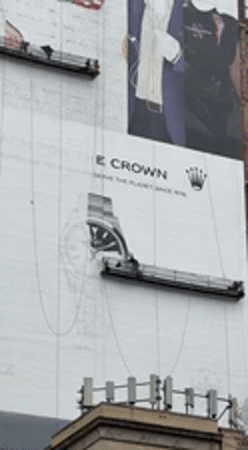 Workers maintain billboard on suspended platform in NYC