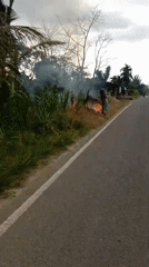 Elderly woman tends roadside fire in rural Indonesia