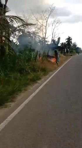 Elderly woman tends roadside fire in rural Indonesia