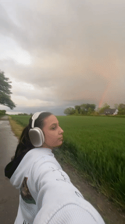 Woman documents rainbow over Mönchengladbach fields during evening walk