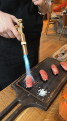 Server flame-sears sushi with torch in Moscow restaurant