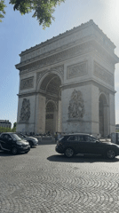 Tourist photographs Arc de Triomphe on clear Paris morning