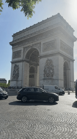 Tourist photographs Arc de Triomphe on clear Paris morning
