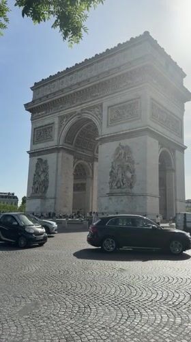 Tourist photographs Arc de Triomphe on clear Paris morning