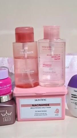 The video shows a collection of skincare products neatly arranged on a flat surface. Prominently featured are two bottles of micellar water: one from The Originote and another from Wardah, both with a pink tint. Below them rests a pink box of Skintific Niacinamide Brightening Daily Masks. To the left, a stacked pair of jars, one in silver from Tazzi and another in pink, can be seen. Completing the arrangement on the right are a Facetology sunscreen bottle and a Viva Whitening Cream tube. The overall presentation conveys a focus on skincare and beauty items.