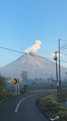 Active volcano looms over a winding road in rural East Java