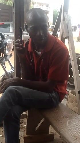 Man makes phone call from workshop bench in Adankolo