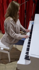 Woman plays white piano in empty auditorium hall