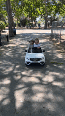 Kids ride a toy Mercedes at a sunny Kiryat Bialik park