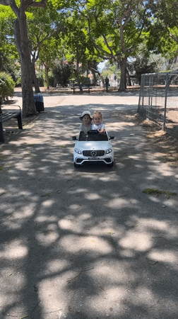 Kids ride a toy Mercedes at a sunny Kiryat Bialik park