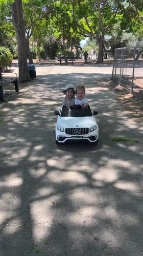 Kids ride a toy Mercedes at a sunny Kiryat Bialik park