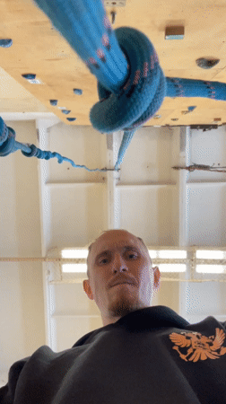 Man observes suspended climbing rope indoors in Sarapul, Russia