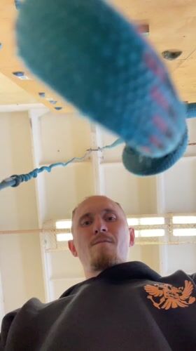 Man observes suspended climbing rope indoors in Sarapul, Russia