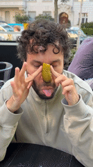 Man plays with pickle at Berlin outdoor cafe
