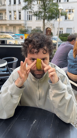 Man plays with pickle at Berlin outdoor cafe